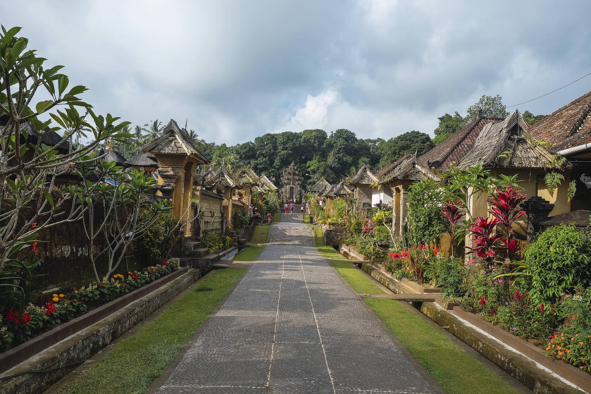 Ulica w Penglipuran na Bali z tradycyjną architekturą i roślinnością.