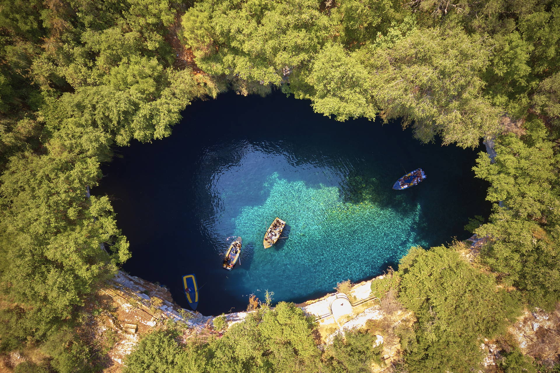 Jezioro Melissani na Kefalonii sfotografowane z lotu ptaka. Na wodzie widać łodzie.
