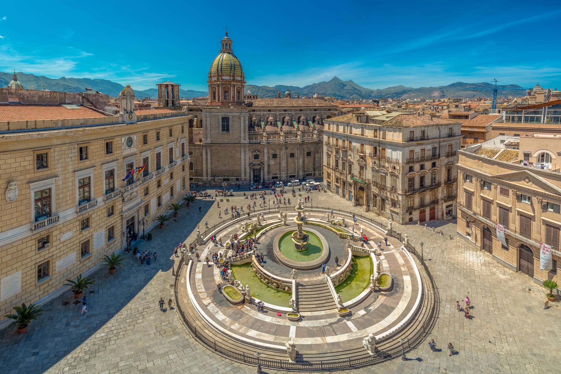 Fontanna na Piazza Pretoria w Palermo, otoczona budynkami i ludźmi.