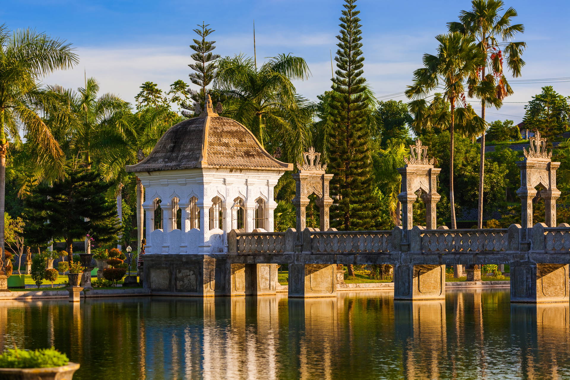 Taman Ujung Water Palace na Bali. Białe budynki otoczone palmami nad wodą.