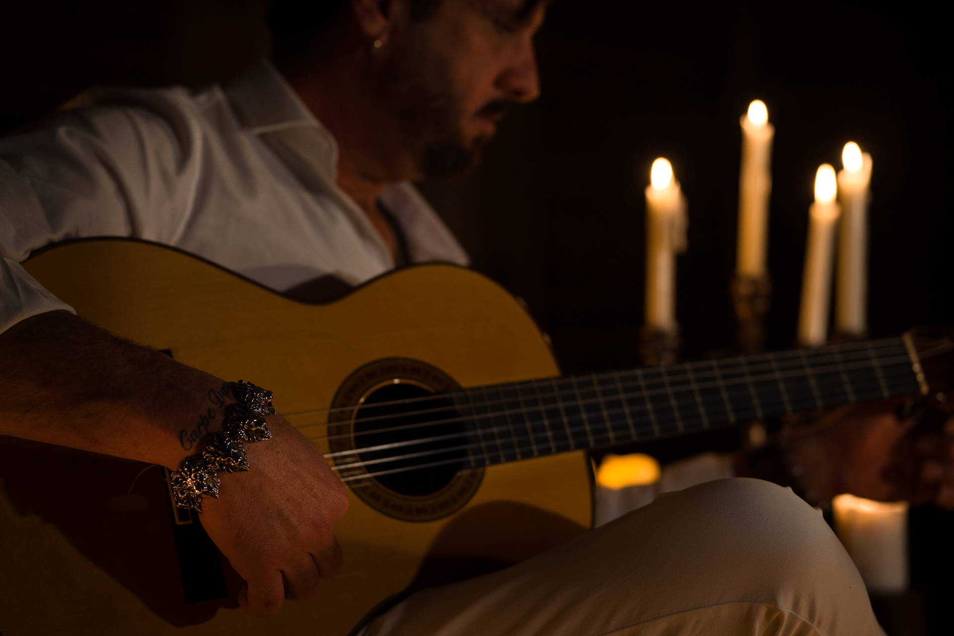Mężczyzna gra na gitarze klasycznej przy świecach.