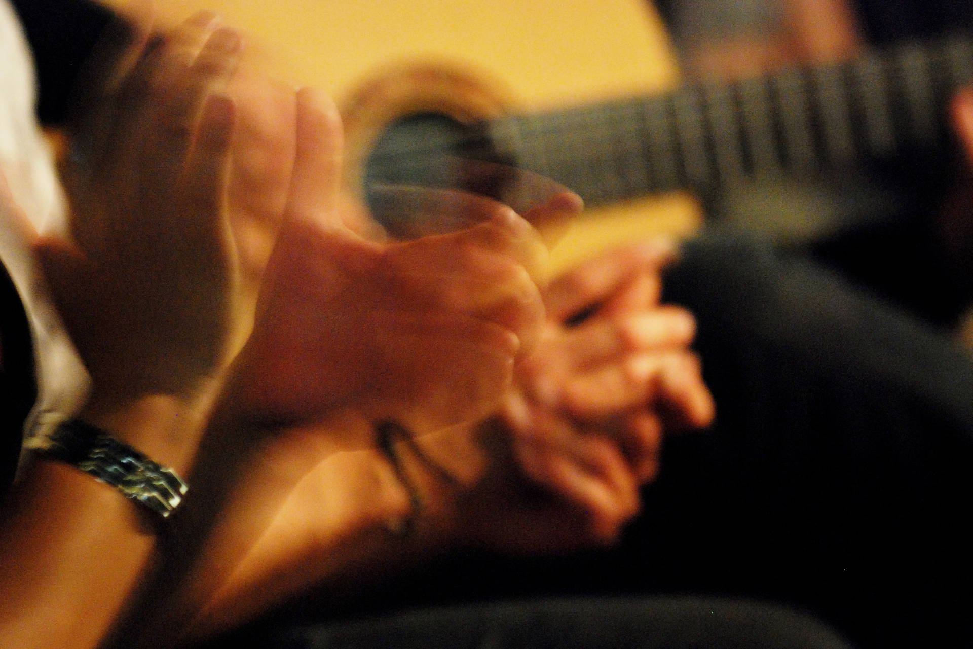 Rozmazane zdjęcie mężczyzny grającego na gitarze i klaszczącego.