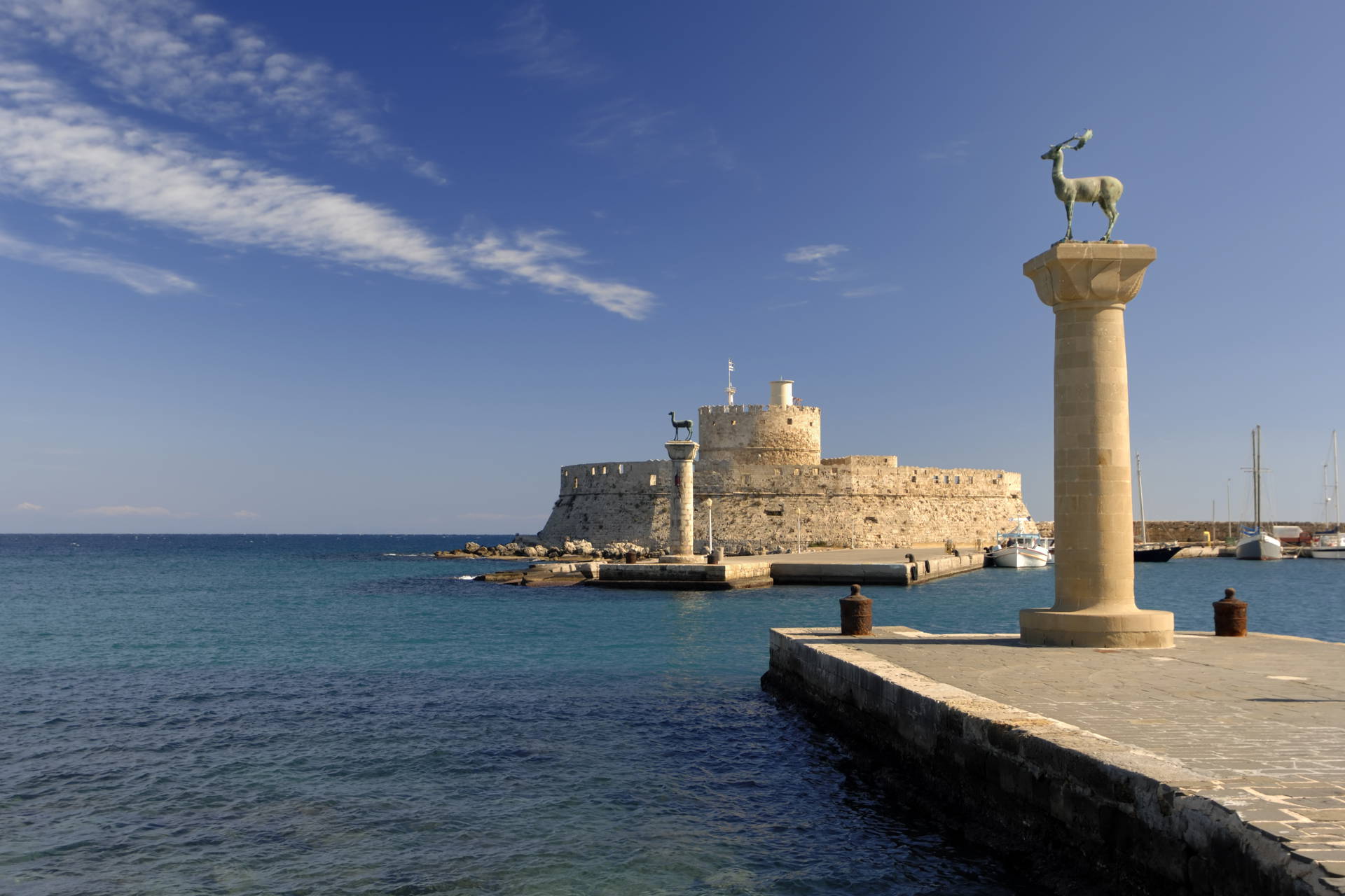 Port Mandraki w Rodos z posągami jeleni na kolumnach.