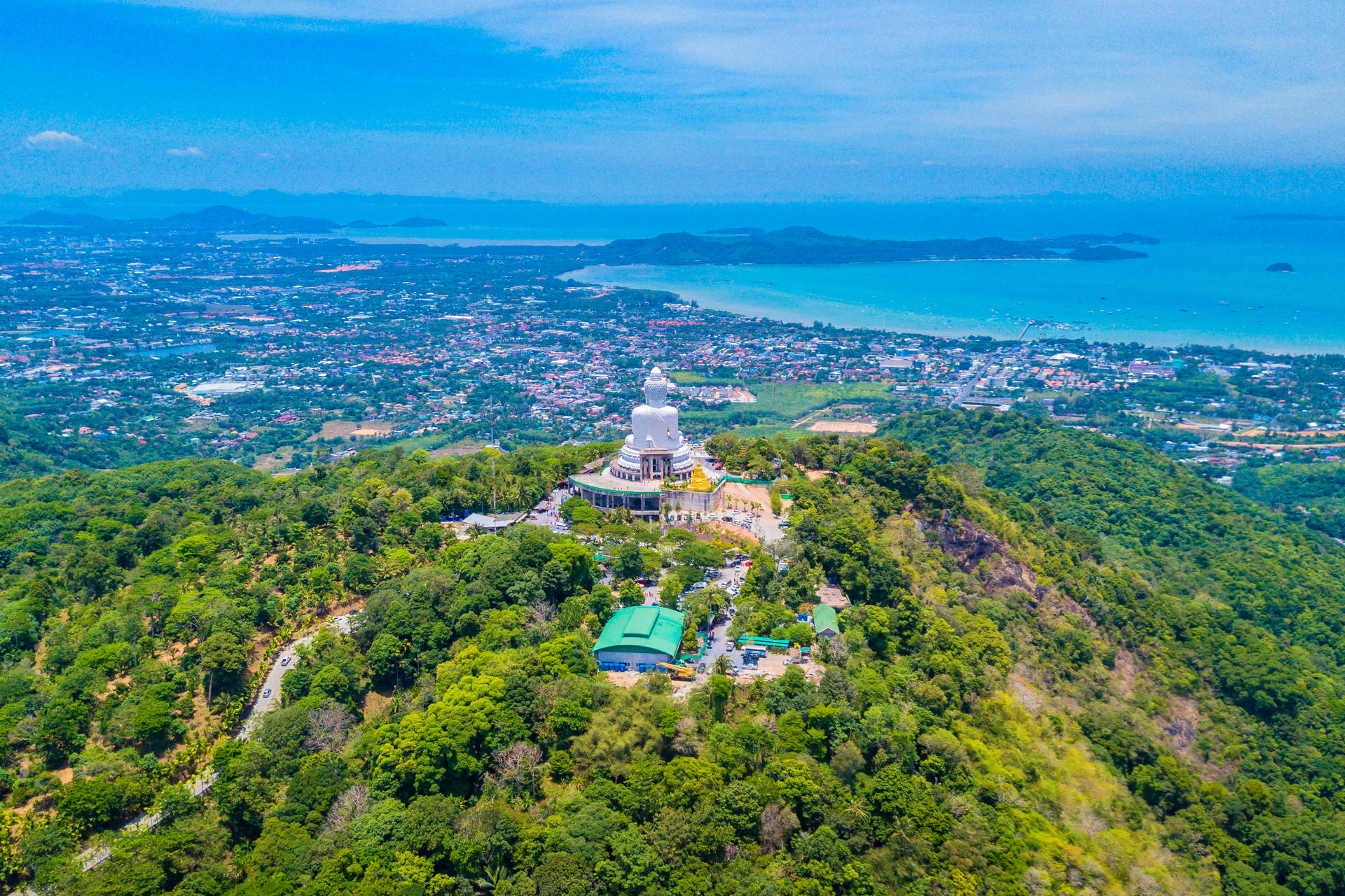 Wielki Budda z Phuket na szczycie zalesionego wzgórza.