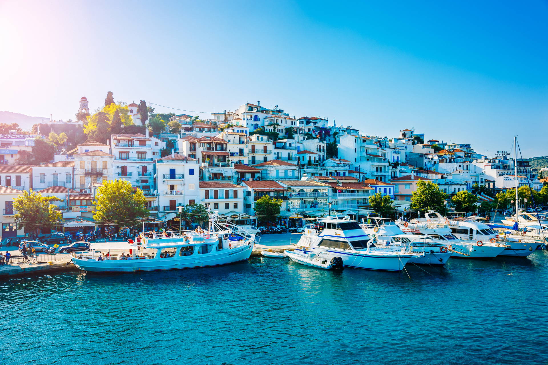 Skiathos, Grecja: łodzie w porcie i białe domy na wzgórzu.
