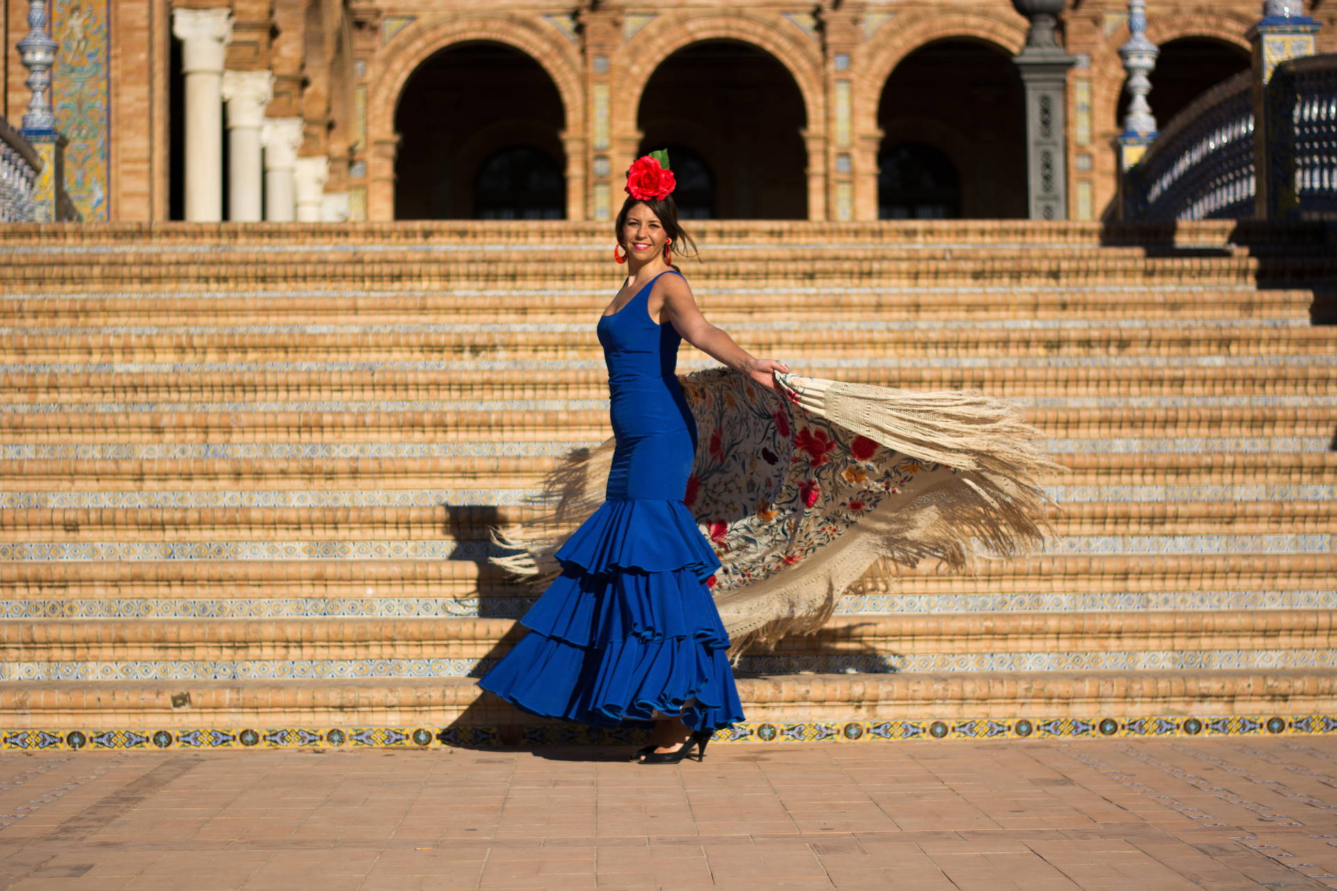 Tancerka flamenco w niebieskiej sukni na tle Plaza de España w Sewilli.