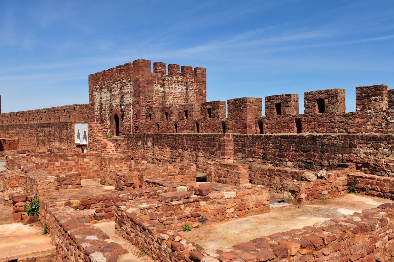 Czerwona kamienna forteca na tle błękitnego nieba. Zamek w Silves, Portugalia.