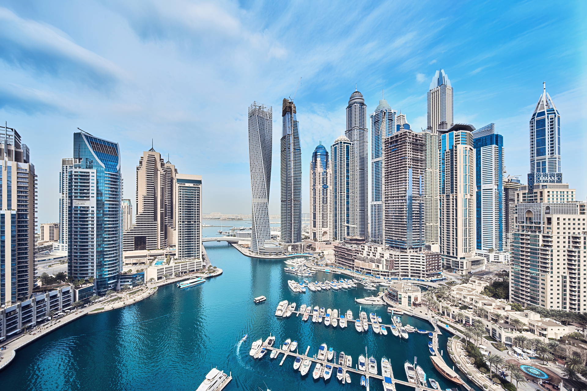 Panorama Dubaju z wysokimi budynkami i zatoką pełną łodzi.