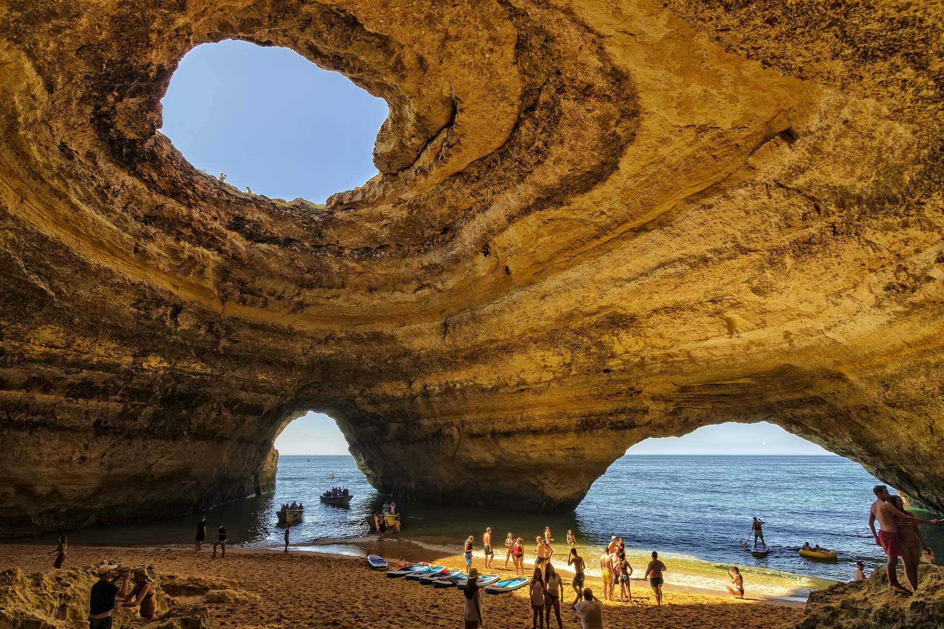 Wnętrze jaskini Benagil w Portugalii z plażą i turystami.