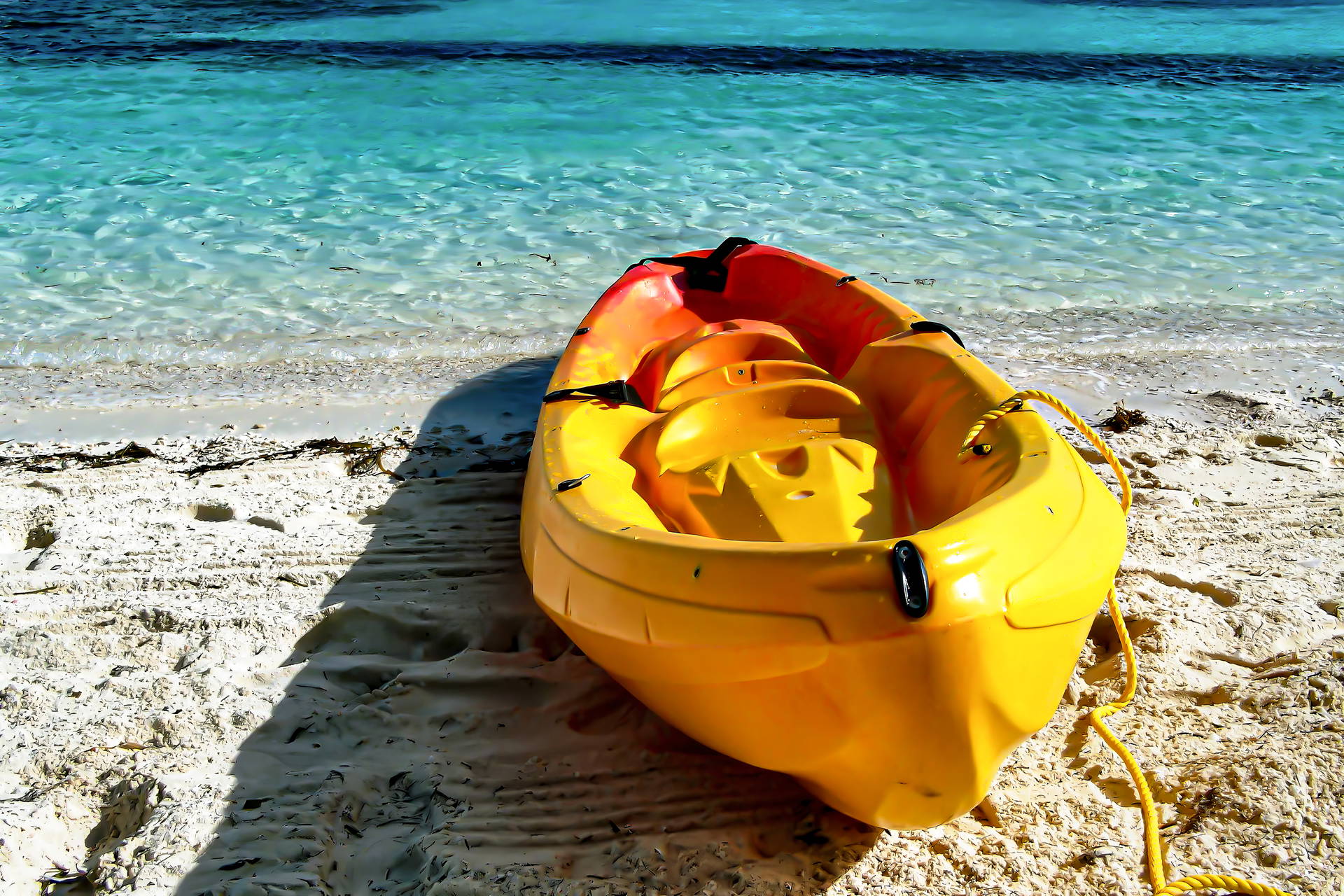 Żółto-pomarańczowy kajak na piaszczystej plaży.