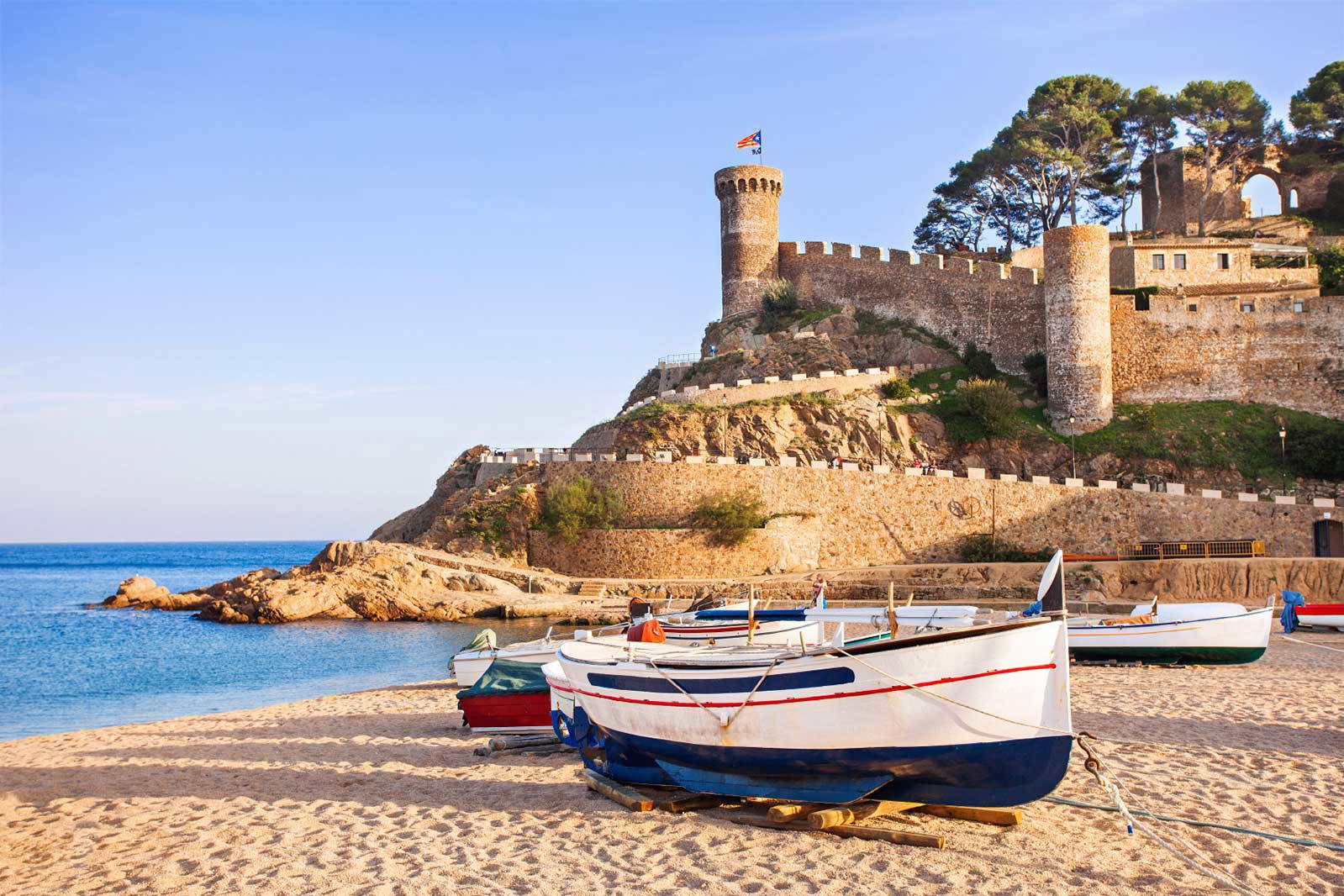 Plaża z łodziami i zamek w Tossa de Mar w tle.