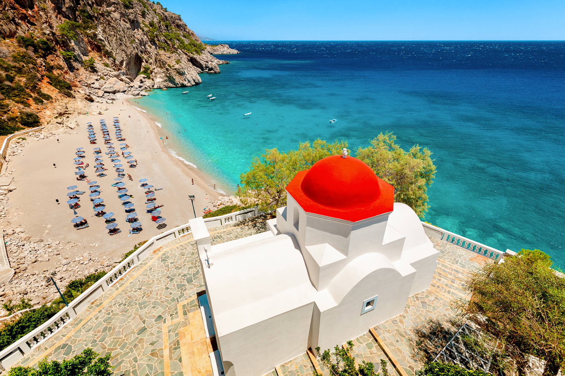 Biały kościół z czerwoną kopułą nad plażą Kyra Panagia i turkusowym morzem na Karpathos.