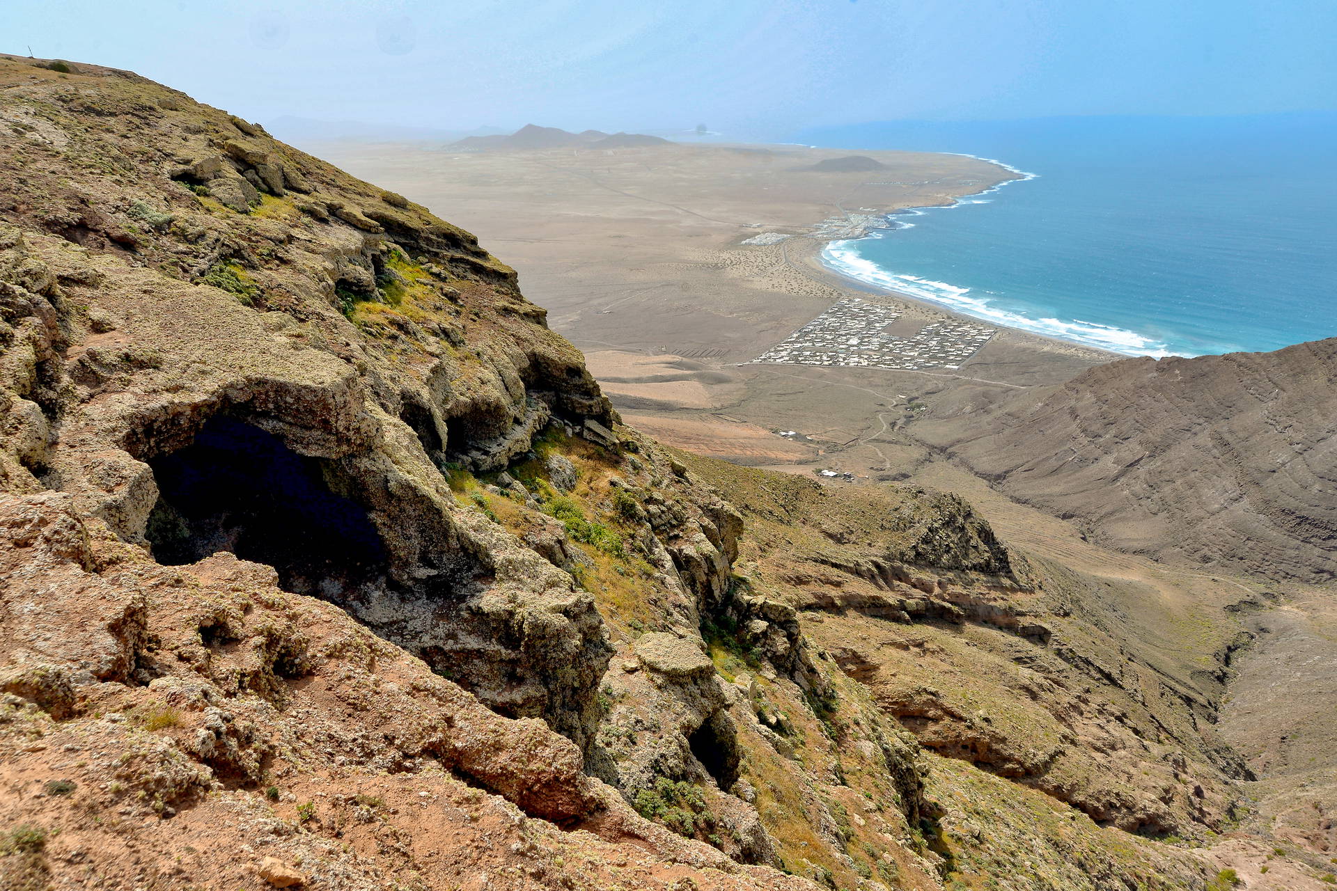Widok na plażę Famara i ocean z wysokiego, skalistego klifu na Lanzarote.