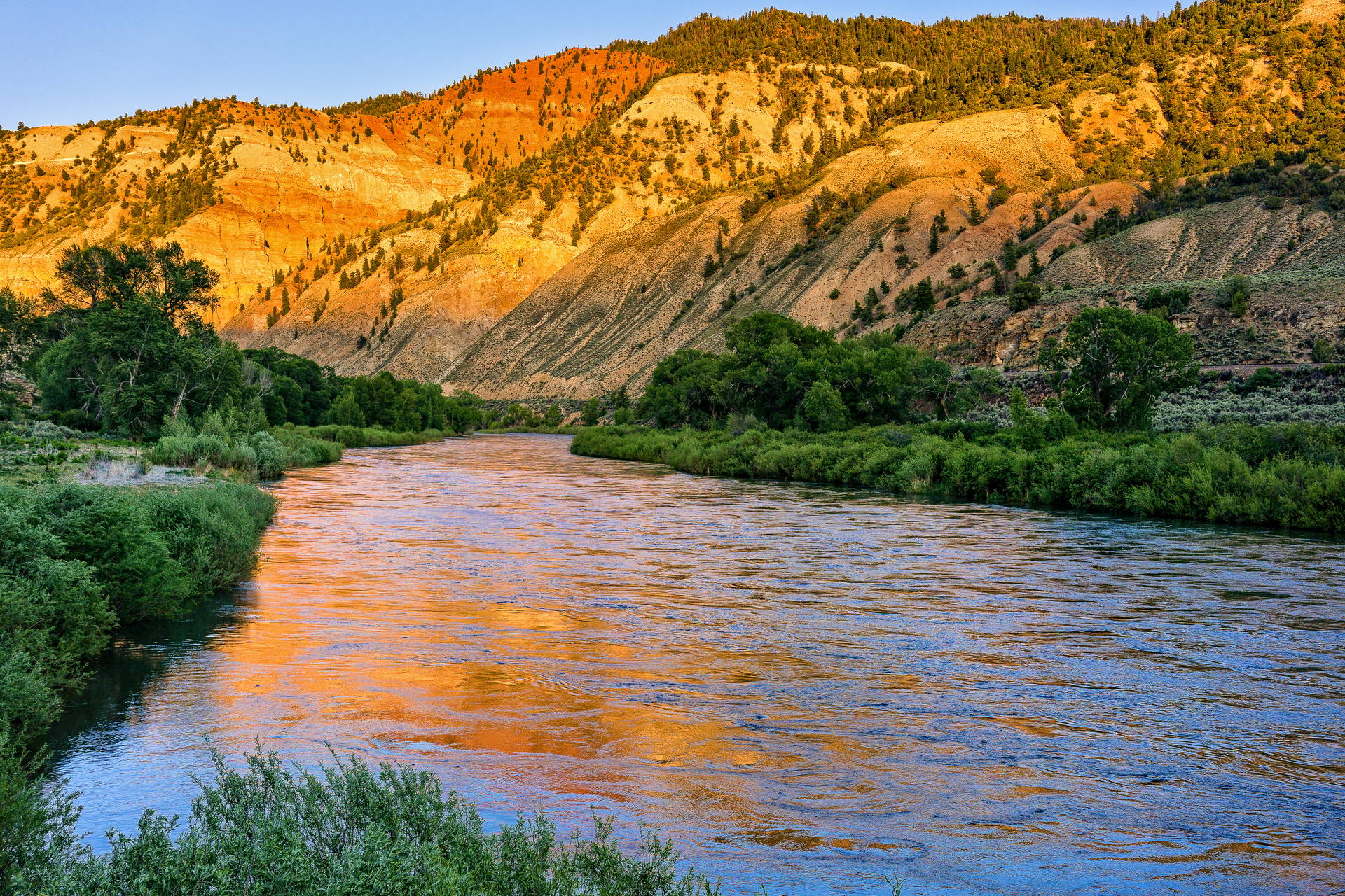 Rzeka u podnóża wzgórz o zachodzie słońca.