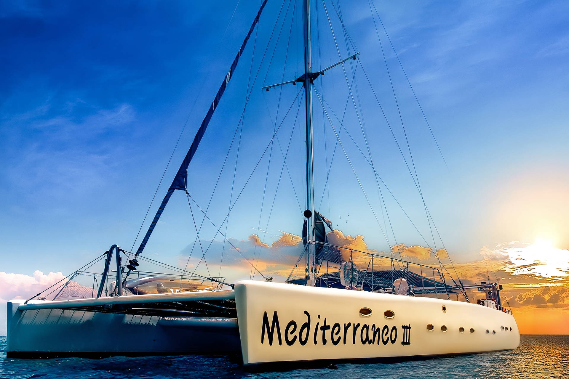 Katamaran "Mediterraneo III" na morzu podczas zachodu słońca.