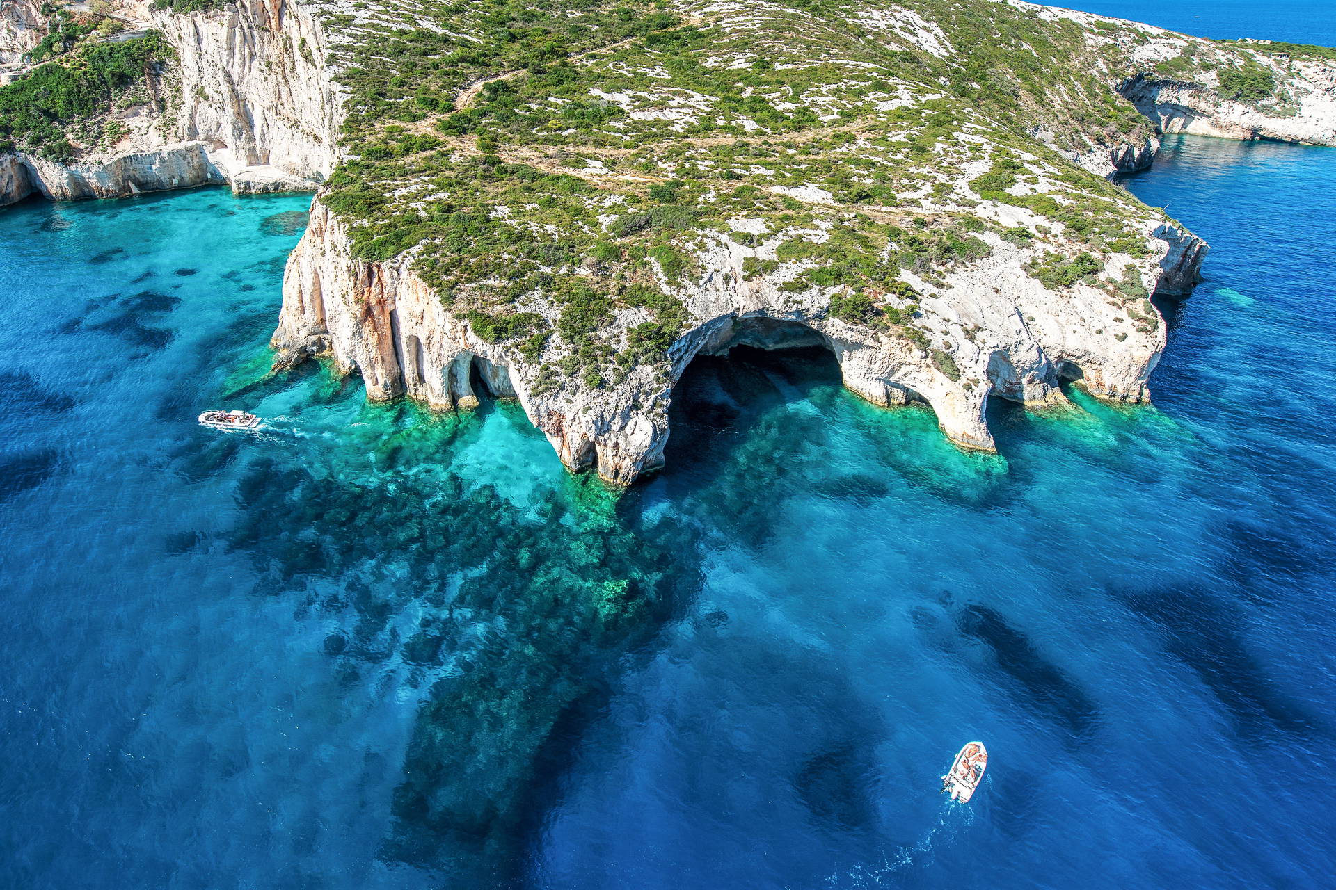 Klify z jaskiniami i łodzie na Zakynthos z lotu ptaka.