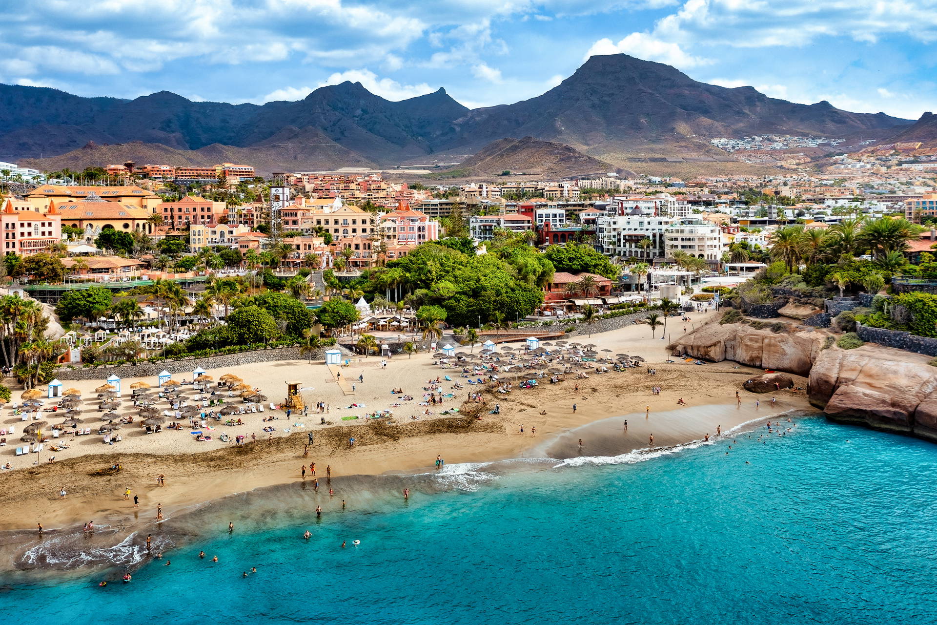 Widok z góry na plażę Playa del Duque w Costa Adeje na Teneryfie. W tle widać miasto w otoczeniu gór.