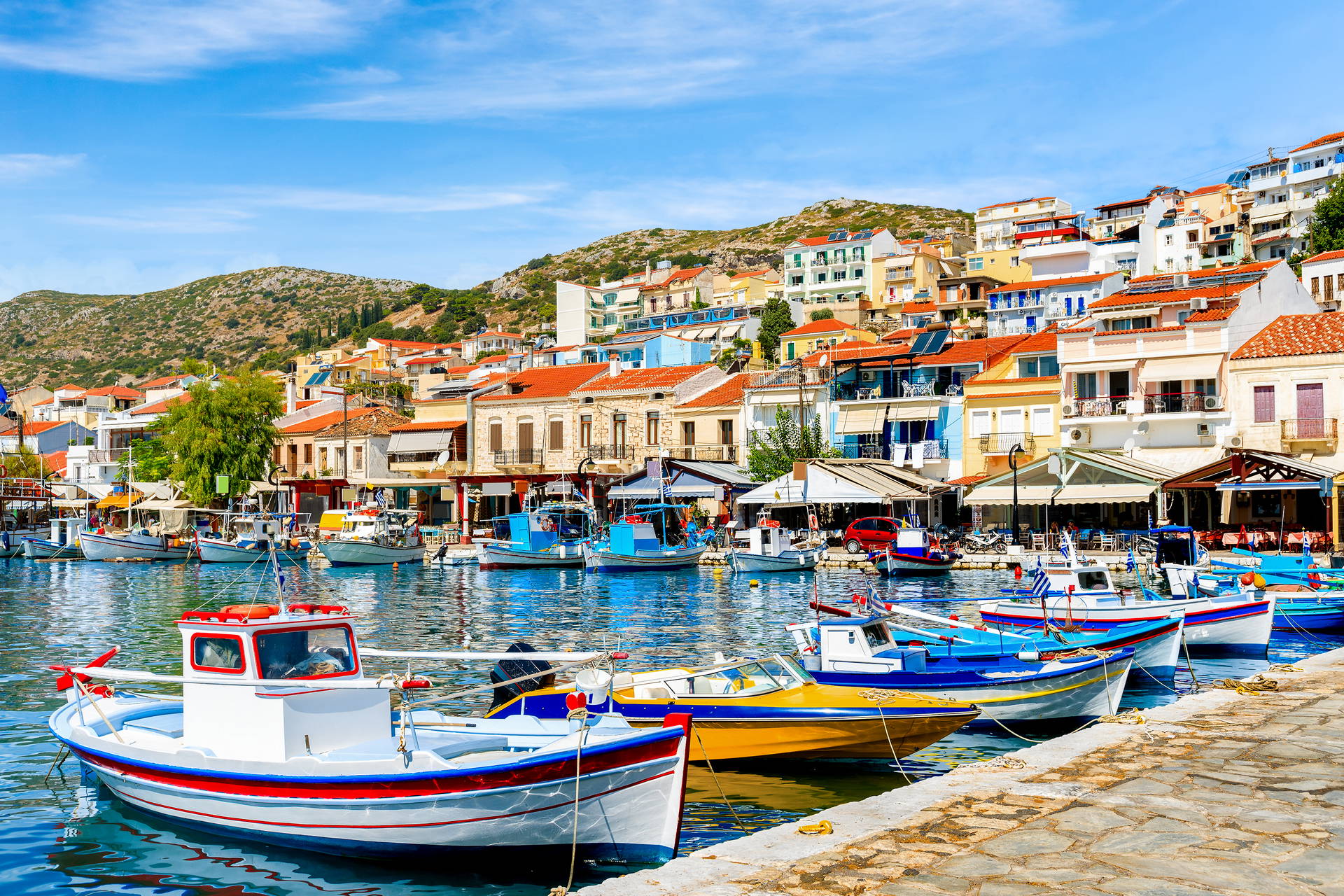 Kolorowe łodzie rybackie w porcie Pythagoreion na Samos. W tle widać miasteczko na wzgórzu.