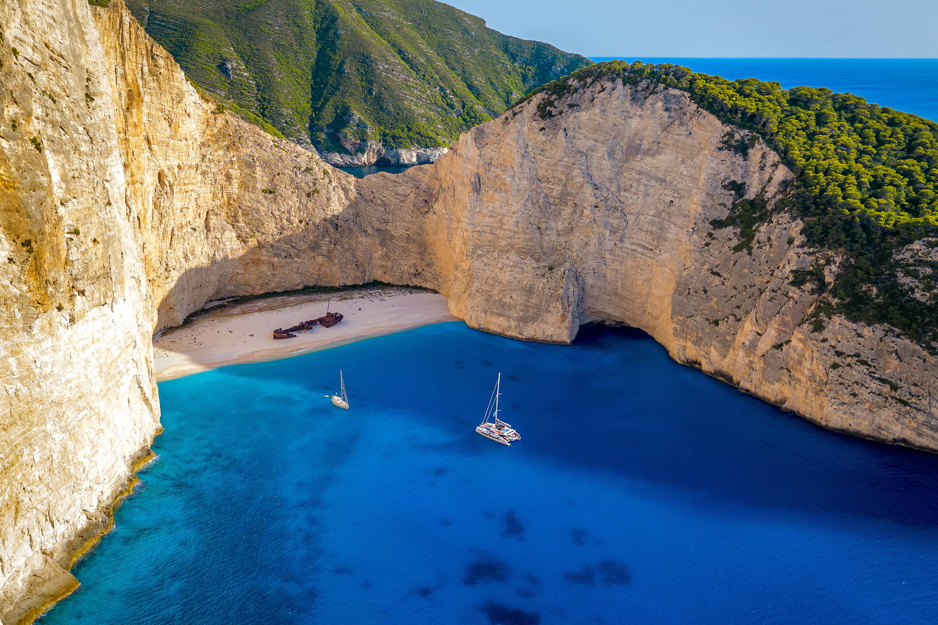 Widok z lotu ptaka na plażę Navagio na Zakynthos. Na piasku leży zardzewiały wrak statku, otoczony klifami i błękitnym morzem.