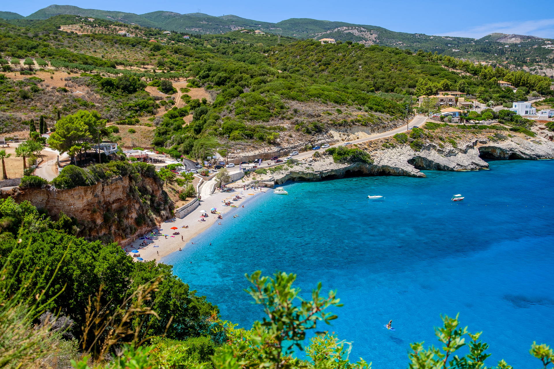 Widok z góry na plażę Makris Gialos na Zakynthos. Mała, skalista zatoczka z turkusową wodą, otoczona zielonymi wzgórzami.