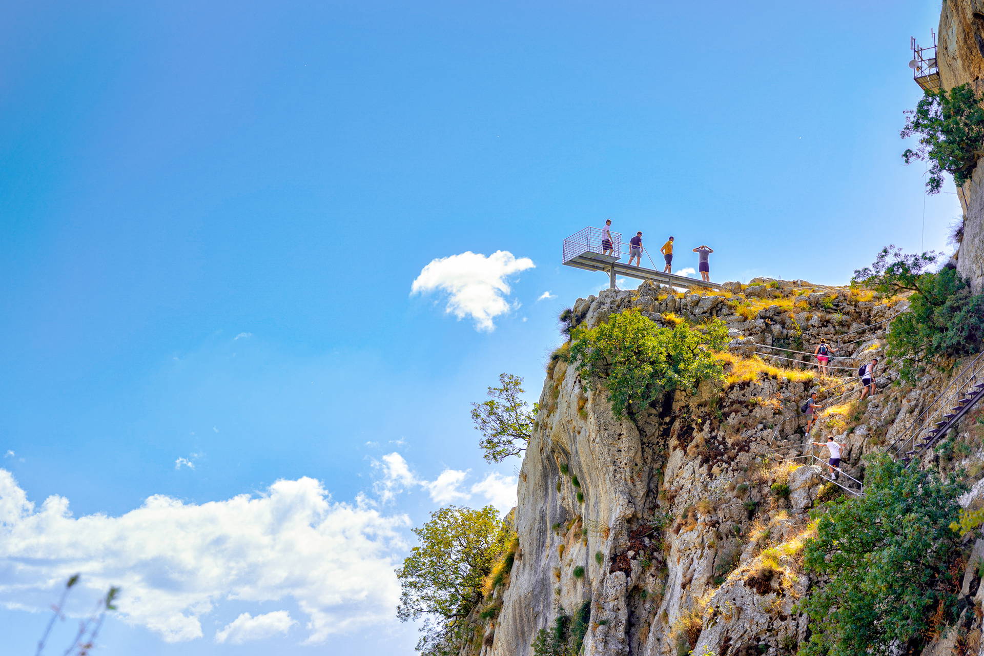 Turyści na platformie widokowej i schodach na klifie – szlak Caminito del Rey w Hiszpanii.