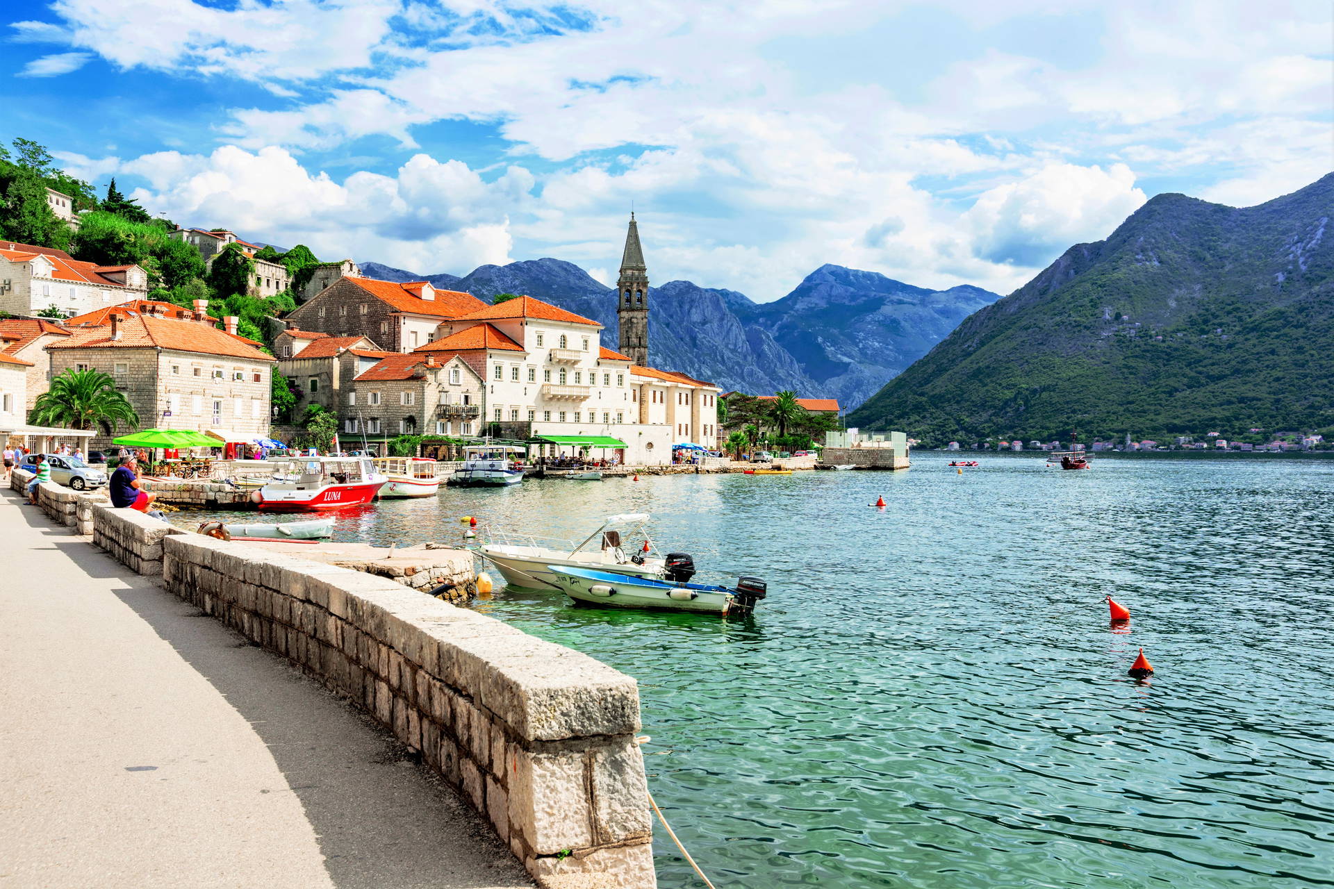 Perast w Czarnogórze widziany od strony morza. Na pierwszym planie łodzie, w tle góry.