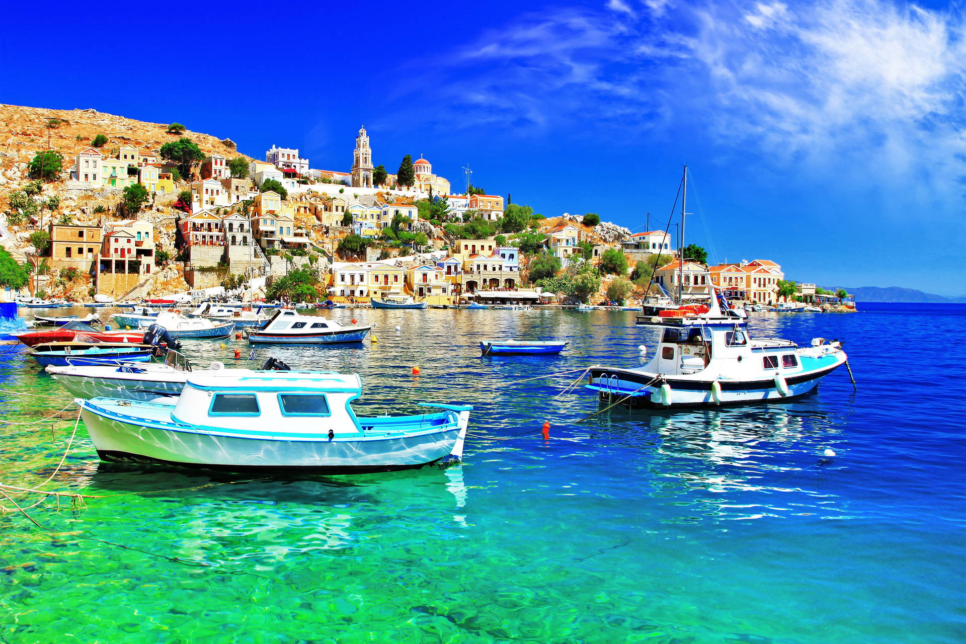 Port Symi w Grecji z łodziami zacumowanymi przy brzegu.