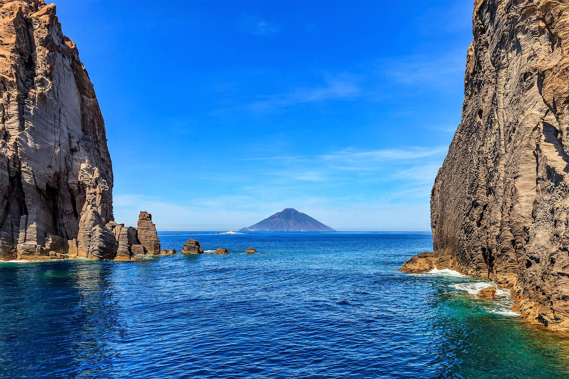 Widok na wyspę Stromboli z łodzi, pomiędzy skałami.