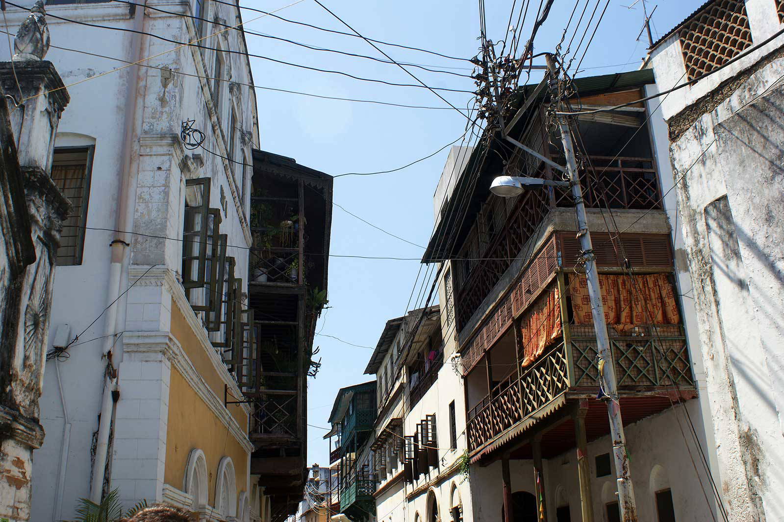 Ulica w Stone Town na Zanzibarze z budynkami o tradycyjnej architekturze i balkonami.