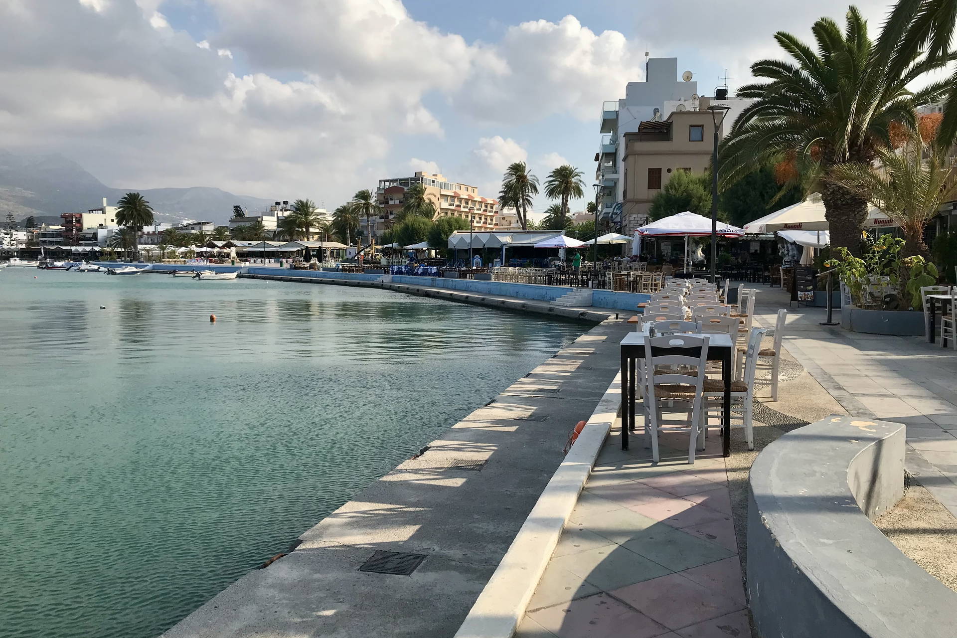 Promenada nad morzem z restauracjami i palmami.