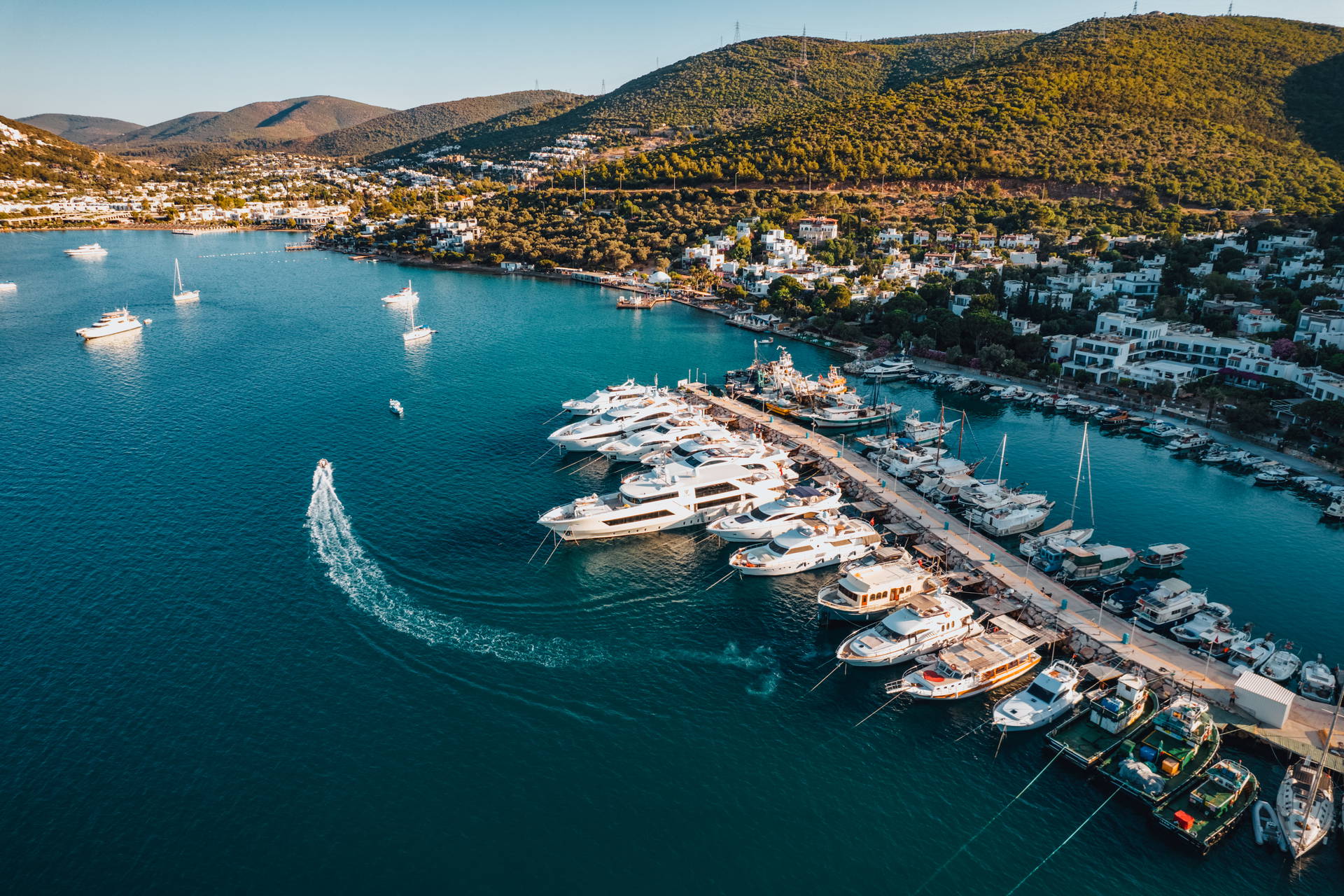 Port jachtowy otoczony zielonymi wzgórzami, widok z lotu ptaka.