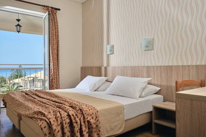 Pokój hotelowy z balkonem i widokiem na morze.
