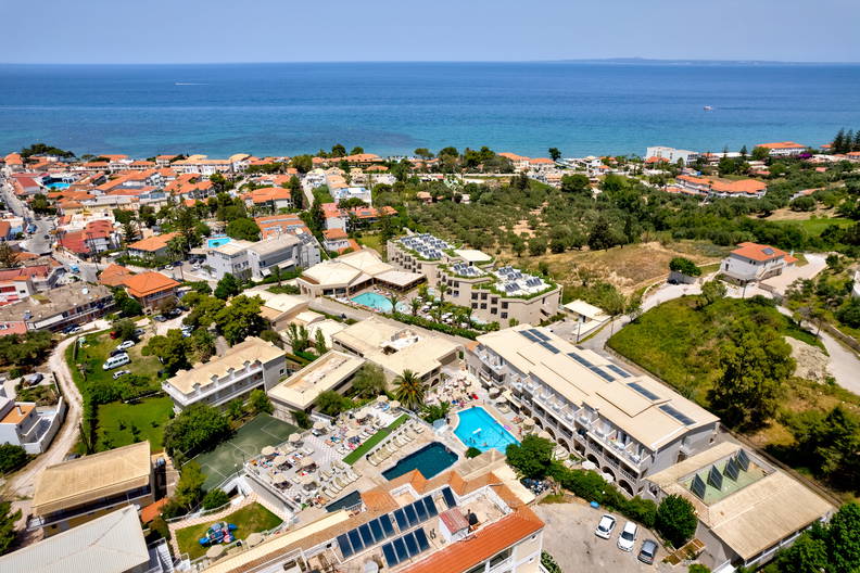 Widok z lotu ptaka na nadmorski kurort z basenami i panelami słonecznymi.