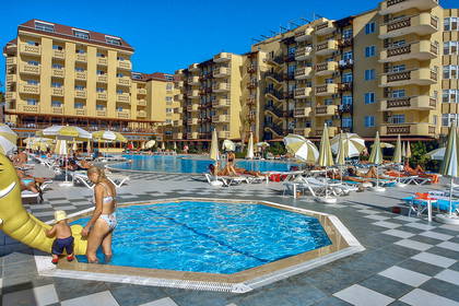 Hotel z basenem, parasolami i wypoczywającymi gośćmi.