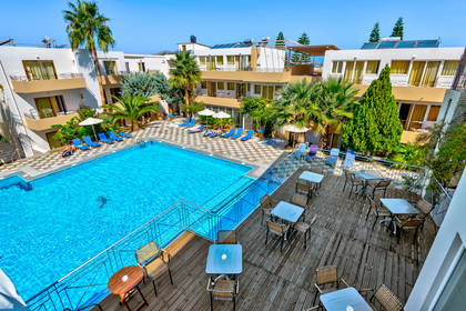 Hotel z basenem, leżakami i stolikami widziany z góry.