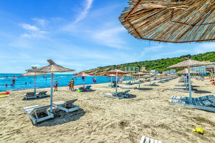Plaża z leżakami i parasolami w słoneczny dzień.
