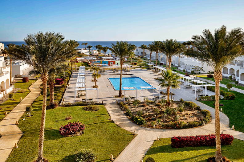 Kurort z basenem, palmami i trawnikami, widok z góry.