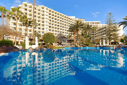 Hotel z palmami odbija się w basenie.