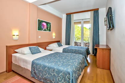 Pokój hotelowy z dwoma łóżkami, balkonem i telewizorem.