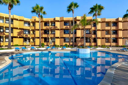 Hotel z basenem otoczonym palmami.