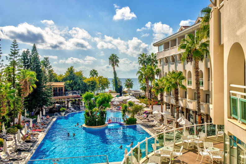 Hotelowy basen z palmami i leżakami w słoneczny dzień.