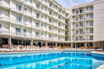 Hotel z basenem, leżakami i balkonami.