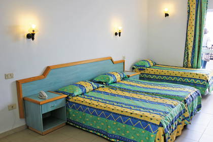 Pokój hotelowy z dwoma łóżkami, szafką nocną i lampkami.