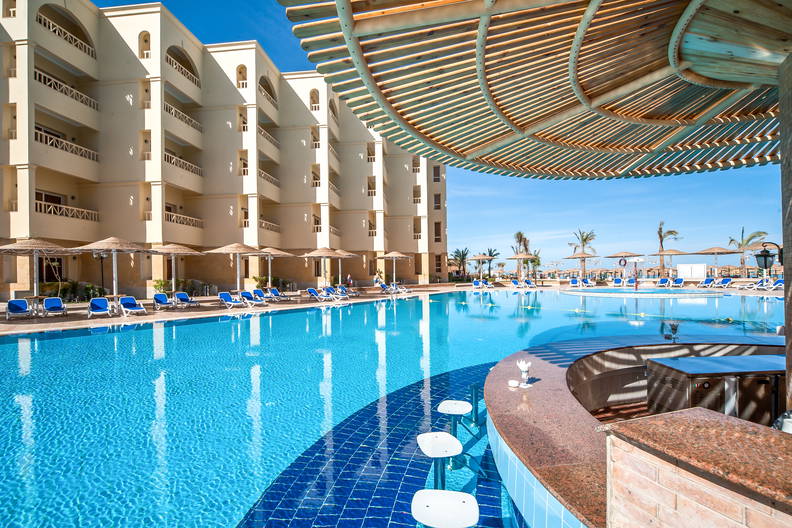 Basen hotelowy z barem wodnym i leżakami.