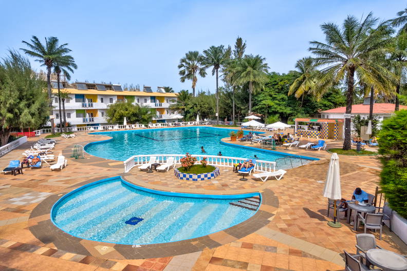 Kompleks basenów z palmami i leżakami w ośrodku wypoczynkowym.