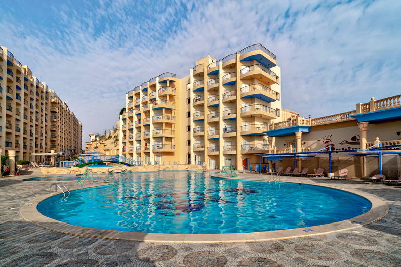 Kompleks hotelowy z basenem w słoneczny dzień.