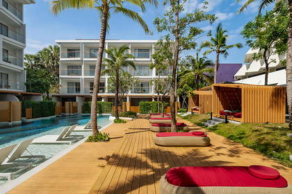 Resort z basenem, palmami i miejscami do wypoczynku na drewnianym tarasie.