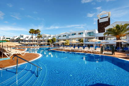 Kompleks hotelowy z basenem i palmami.