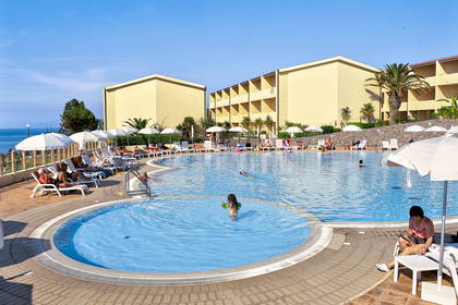 Kompleks hotelowy z basenem i wypoczywającymi gośćmi.