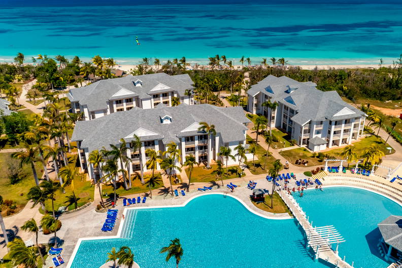 Resort z basenem, budynkami i plażą widziany z lotu ptaka.